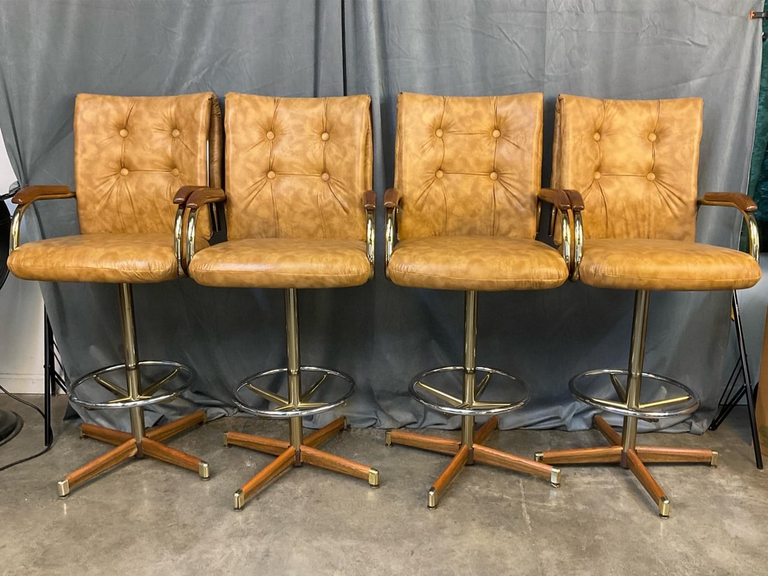 : Set of four matching tufted, faux leather, swivel barstools. Made by Daystrom.Tan fabric, metal base, and wood arm rests. All in good condition. Each one measures 21 inches wide x 21 x 49 inches tall.