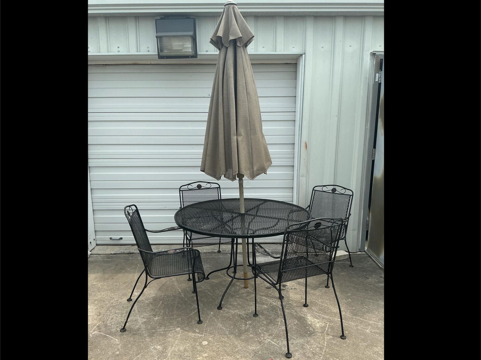 Wrought Iron Patio Set: Patio set with umbrella, stand, and four chairs. Needs proper cleaning and there is paint loss present. Table measures 46 inches in diameter x 30 inches tall.