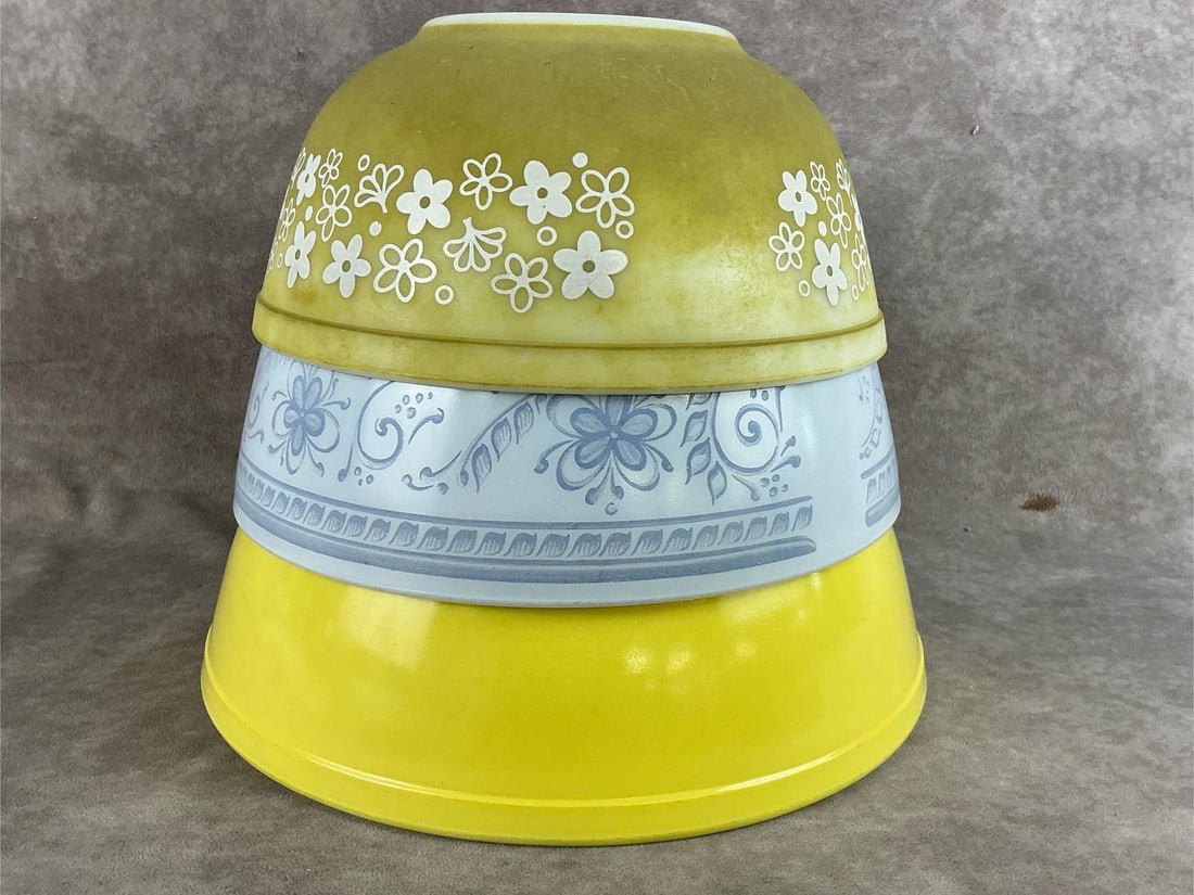 Pyrex Trio: Large yellow bowl, medium Brittney Blue and a smaller Spring Blossom Crazy Daisy. The Crazy Daisy is in poor condition and the varnish is completely gone. Otherwise good condition. Largest bowl measur
