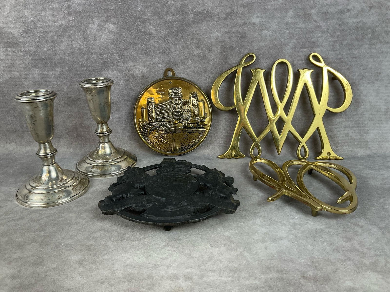 Sterling Candlesticks & VA Metalcrafters Trivets: Set of weighted sterling candlestick holders made by Crown. Three Virginia Metalcrafters trivets. 1950 brass William and Mary Cypher, 1950 brass Greenbrier Cypher, and a black iron 1950s Kings Arms tr
