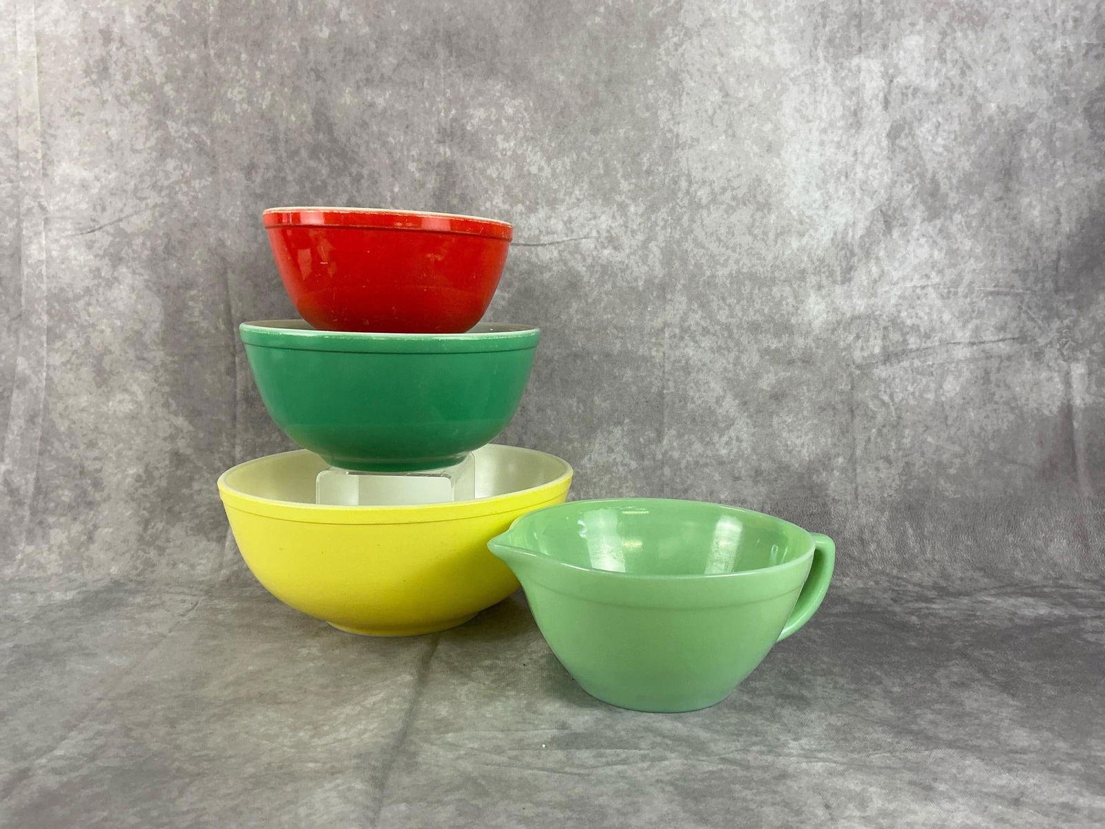 Pyrex & Jadedite: Set of primary colors nesting bowls, with heavy use and one Fire King handled mixing bowl, in good condition. Largest Pyrex bowl measures 9.5 inches in diameter x 5 inches tall.
