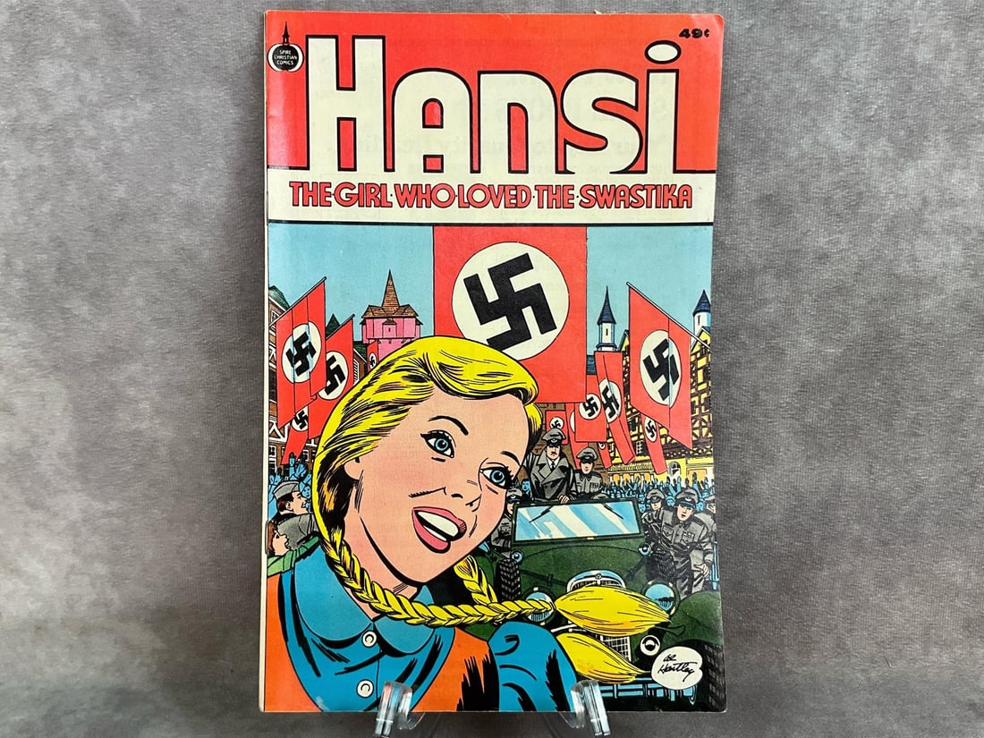 Hansi Swastika Comic: 1976 The Girl Who Loved the Swastika comic book by Spire Comics printed in the USA. Comic is in fair to good condition, soft corners and some fixing around edges. Comes with protective sleeve. Measure
