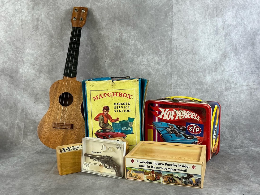 Vintage Hotwheel & Matchbox Toys: 1966 Matchbox Garage Service Station, 1969 Hot Wheels lunch box, souvenir revolver, Melissa and Doug wooden puzzles, dominoes, and a child's guitar. All items are fair to good condition. Matchbox Gara