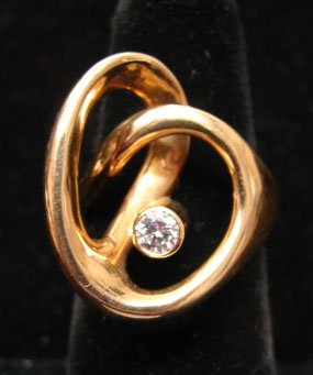 Ole Lynggaard Jewelry: Ole Lynggaard stylized interlocking ring with accent diamond (.20cttw). 18k yellow gold. Marked "OLEL 750 18k." Model # 472-4. 15.5 grams total weight. Comes with original Lynggaard tag. Original reta