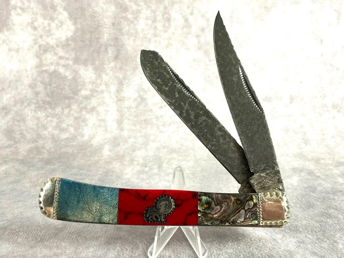 Brian Yellowhorse Trapper Knife: Brian Yellowhorse native steel trapper inlayed with desert ironwood and accented with mother of pearl. In good conditon with COA and display box. Knife measures 4 inches closed, box measures 6.5 inche