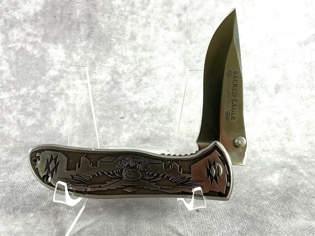 David Yellowhorse Sacred Eagle Custom Knife: Spring assist knife, with his designs engraved into stainless steel, with hand textured surrounds. Signature etched into blade. Made in 2024. Never sharpened or carried. Comes with COA and original bo