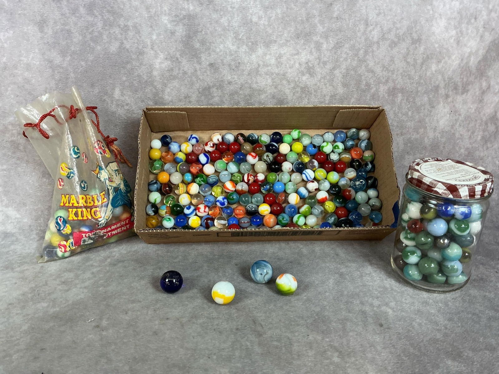 Vintage Glass Marbles: Mid century marbles. Large assortment of glass marbles including Swirls, Agate Parrot, and more. Partial bag of 1950s Marble King Tournament marbles. In good condition. Box measures 12 inches long x 2