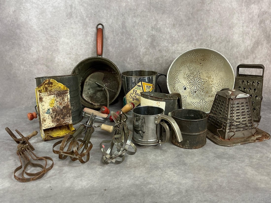 Vintage Metal Kitchen Tools: Thirteen early to mid 1900s kitchen tools. Includes strainer, sifters, egg beaters, and graters. Some are dented and rust present. Poor to fair condition. Large strainer measures 9 inches in diameter