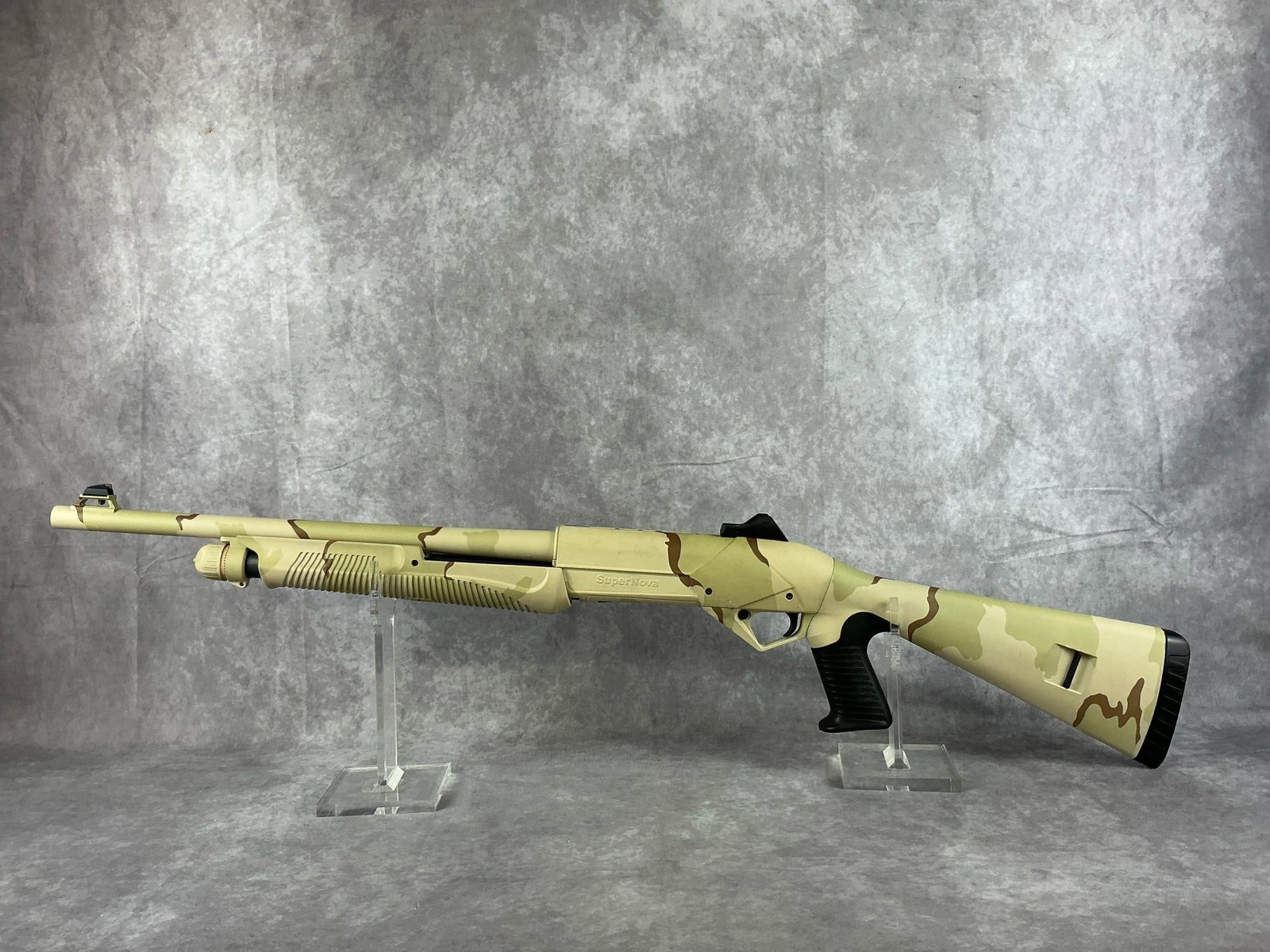 Benelli SuperNova 12GA Tactical Pump Shotgun: Serial number Z493627. Desert camo print with pistol grip. In good condition, shot minimally. Includes original box. Barrel measures 18 inches long, gun measures 40 inches total. Box measures 40 inche