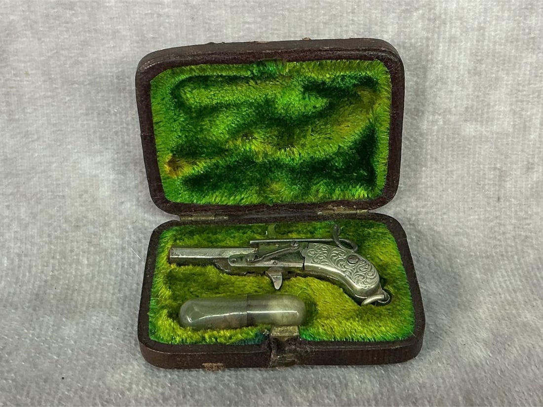 Late 1800s miniature pinfire pistol with hexagonal breach-loading barrel, two piece decorated pistol: Late 1800s miniature pinfire pistol with hexagonal breach-loading barrel, two piece decorated pistol grips. In original brown leather and green velvet-lined fitted box with clearing rod, and tube of b