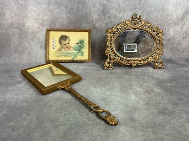 Late 1800s to mid 1900s lot. Oval mirror with gilt baroque style footed frame and handheld square