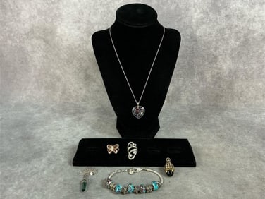 Two art glass necklaces set in sterling and on sterling chains. Two size 7 sterling rings. A charm