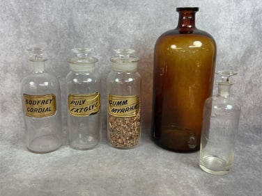 Five late 1800s to early 1900s bottles. Amber colored bottle, three spice jars the glass stoppers