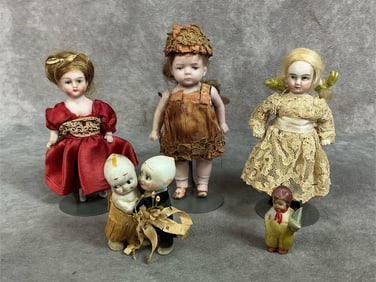 Five late 1800s to early 1900s dolls. Three small bisque dolls on stands, doll in orange flapper