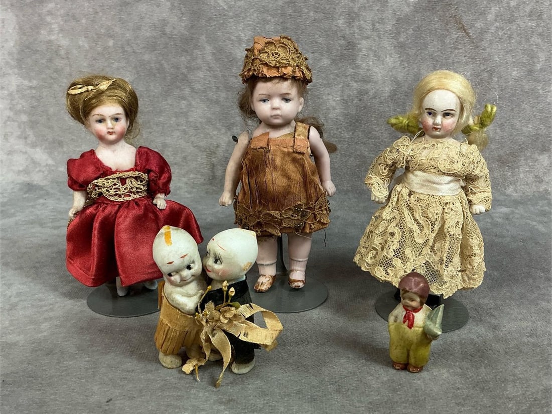 Five late 1800s to early 1900s dolls. Three small bisque dolls on stands, doll in orange flapper: Five late 1800s to early 1900s dolls. Three small bisque dolls on stands, doll in orange flapper dress is a Kestner. Includes bride and groom Kewpie dolls and miniature frozen Dutch boy. Dolls show we
