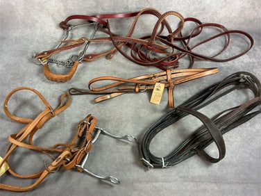 Four vintage leather bridles. Dark brown reins with metal buttons, and red tone bridle with