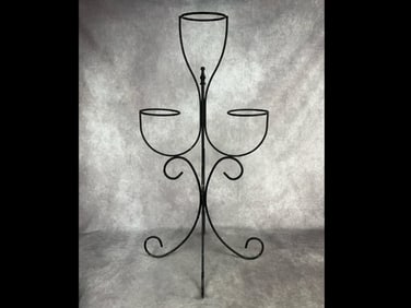 Modern metal plant stand painted black with three spots for potted plants. Paint is chipping in