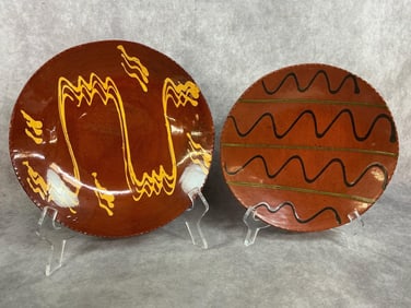 Two signed Lester Breininger redware slip glaze plates. Largest plate was made in 1982, smaller in