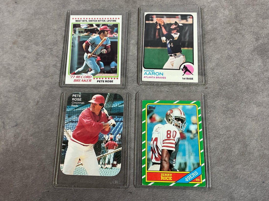 Four 1960s to 1980s cards. Two Pete Rose baseball cards, Hank Aaron Topps card, and Jerry Rice Topps: Four 1960s to 1980s cards. Two Pete Rose baseball cards, Hank Aaron Topps card, and Jerry Rice Topps card. In plastic sleeves. Good condition. Measures 3 inches x 4 inches.