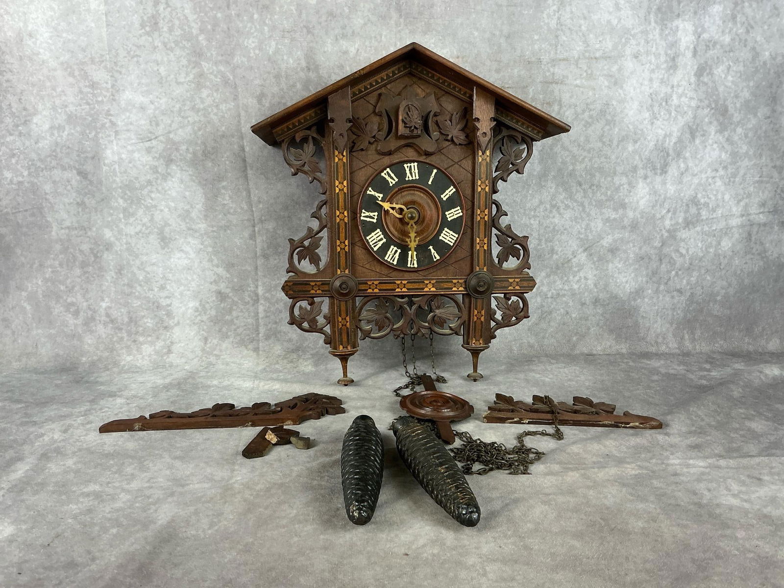 Black Forest Cuckoo Railway Clock: An early 20th century carved walnut and marquetry German Black Forest Railway Cuckoo wall clock. Weight movement with Roman numerals. Crest rails need repair and reattachment. Contains wooden pendulum