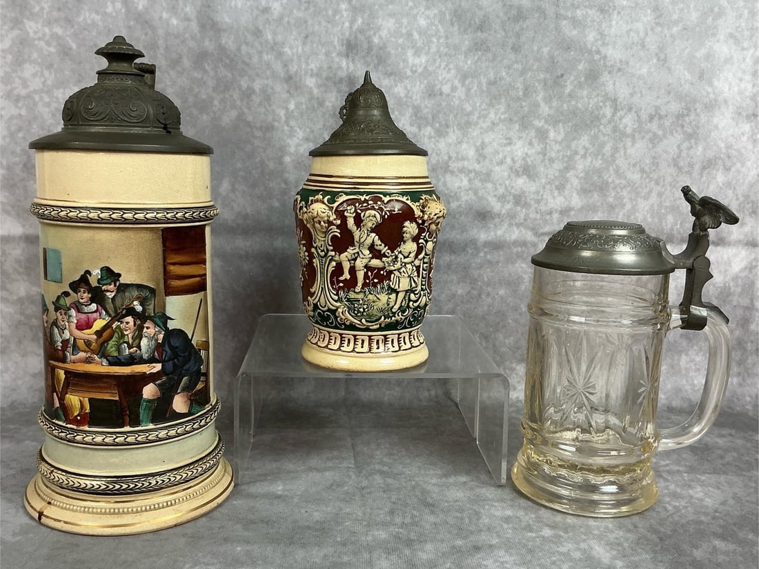 German Beer Steins: Three antique German beer steins with pewter lids. Pressed glass stein with engraved lid, eagle, and marked with a crown on bottom. The two others are marked Germany on bottom, both have crazing. Larg