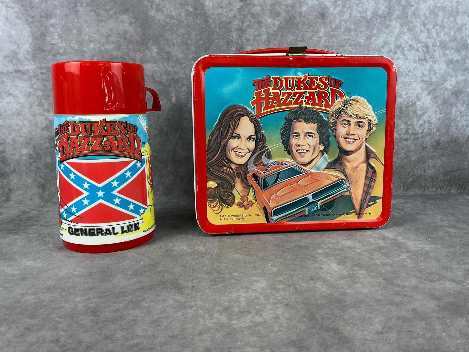 "Dukes of Hazard" Lunchbox: One 1980 "The Dukes of Hazard" Aladdin Industries metal lunchbox with plastic thermos. Minor wear with small dent under latch on front lid above "Dukes" Otherwise good condition. Thermos good conditio