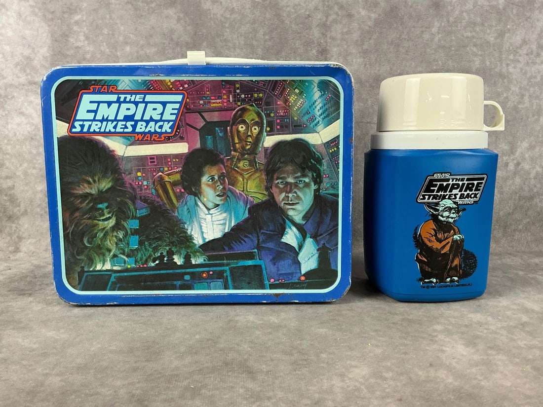 "The Empire Strikes Back" Lunchbox: One 1980 " Star Wars The Empire Strikes Back " metal King-Seeley Thermos Company lunchbox with plastic thermos. Several small areas of rust with several small dents to front lid. Lunchbox measures 8.7