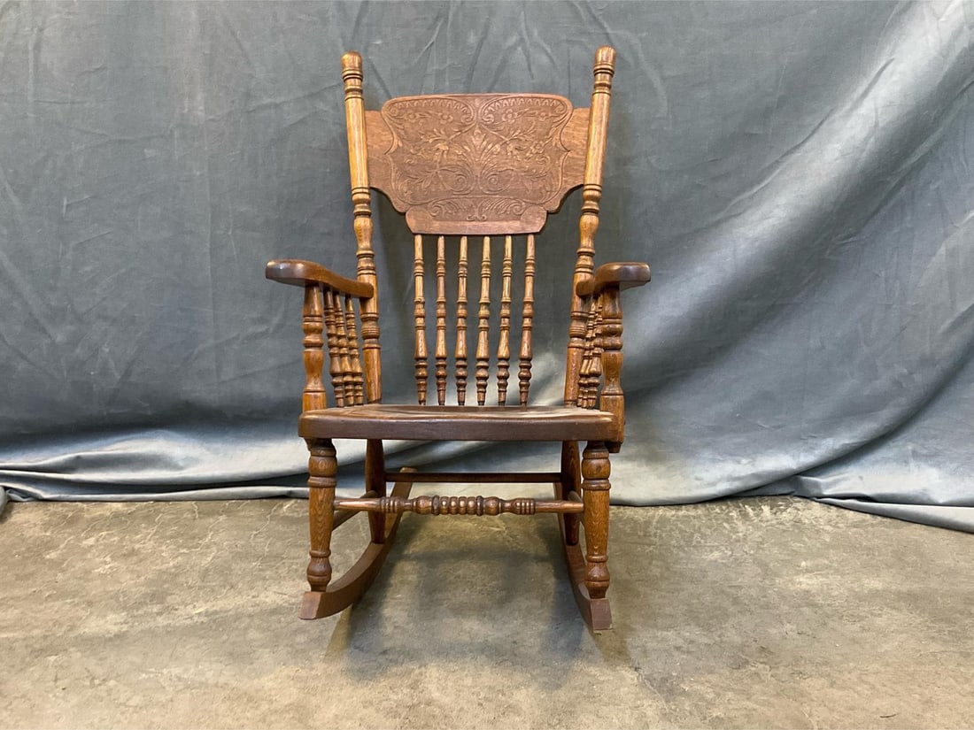 Child's Rocking Chair: Early 20th century child's pressed back oak rocking chair. Wooden seat, turned spindles and turned front rung. Good condition. Measures 15.5 inches wide x 23 x 29 inches tall.