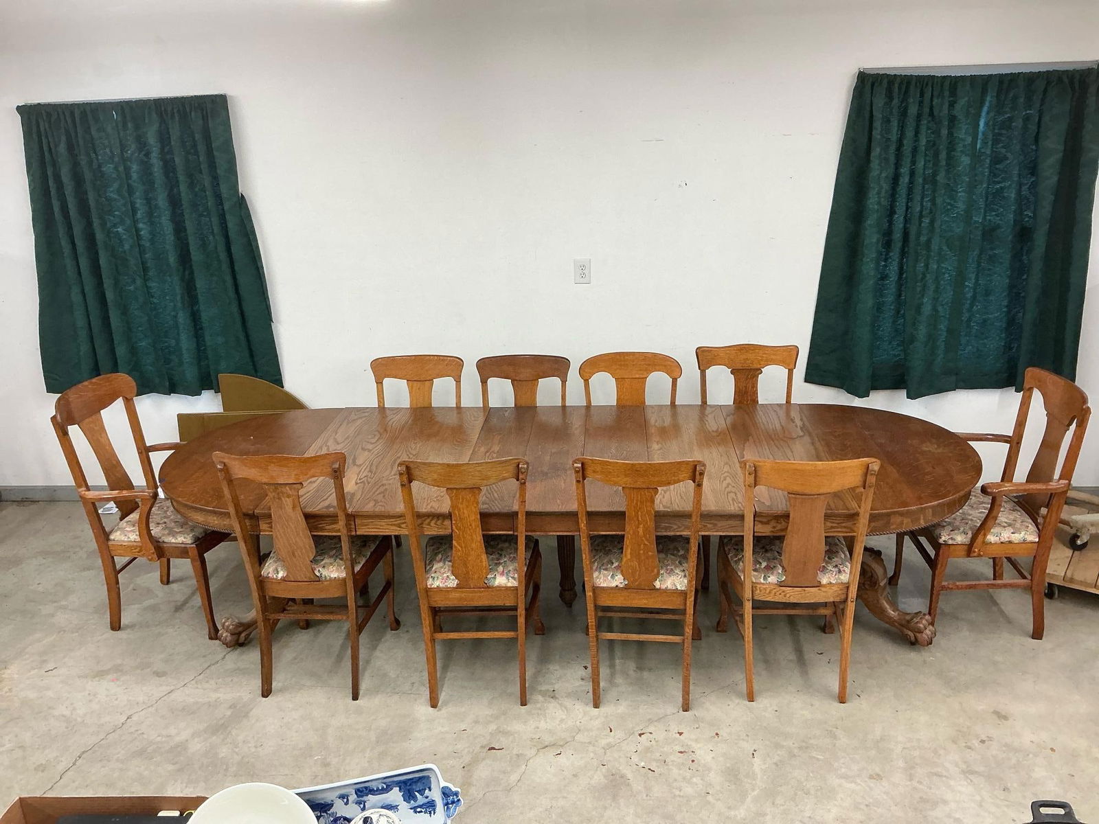 Quarter Sawn Oak Table and Chairs: Early 20th century quarter sawn oak round dining table with extensions, table top protective felt covered pads, and set of eleven chairs. Table resting on pedestal base with carved claw feet and carve