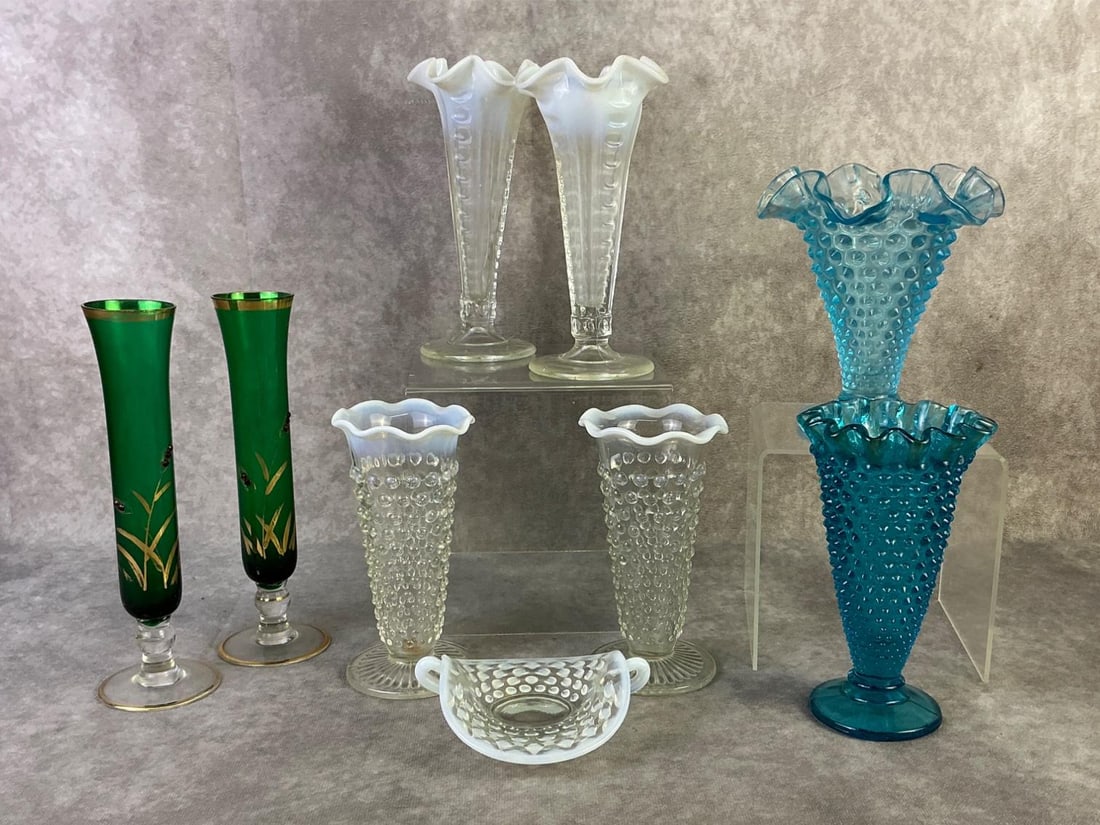 Anchor Hocking, Fenton, & More: Lot of four Anchor Hocking moonstone opalescent hobnail footed vases, a pair of emerald green fluted bud vases, a Fenton blue hobnail ruffled vase and more. All in good condition. Largest measures 3 i