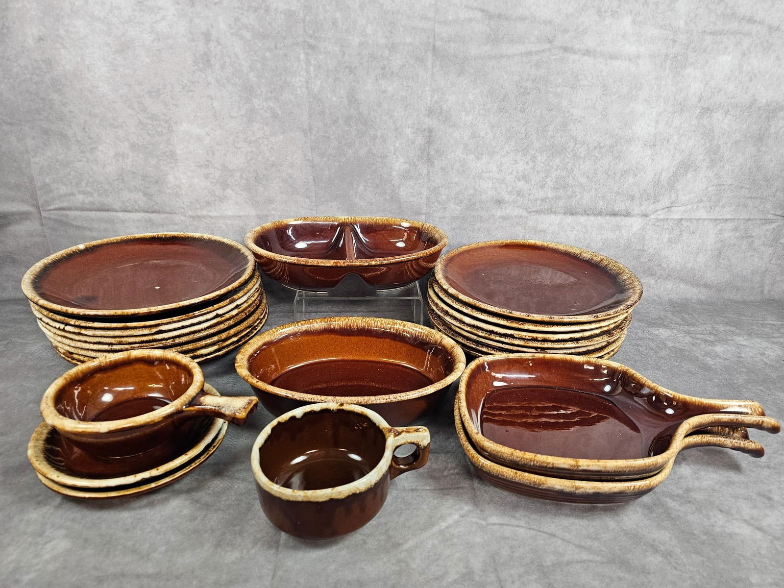 Hull Brown Drip Pottery: Twenty three pieces of Hull brown drip pottery. Includes fifteen 10.5 inch dinner plates, divided dish, soup bowls, and more. Chip to a couple plates, otherwise good condition. Divided dish measures 1