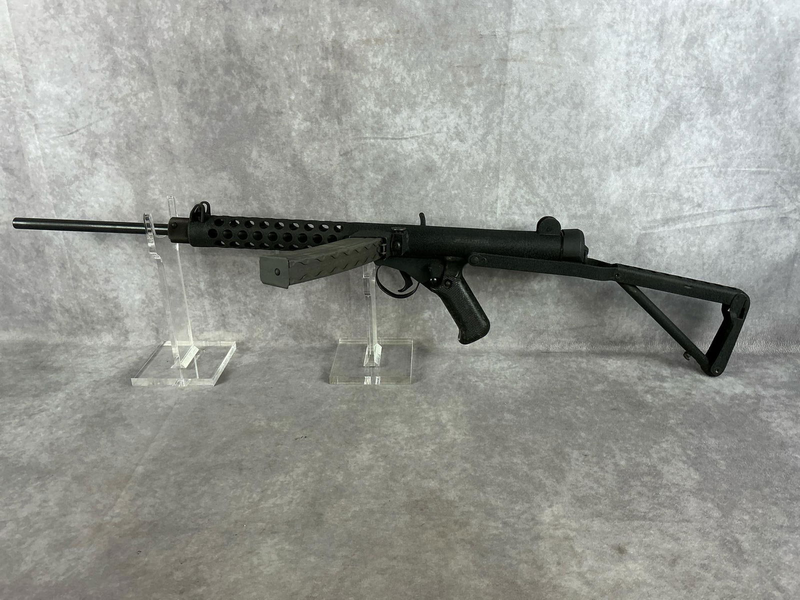 Sterling SMG 9 MM Pistol: Serial # LA29-C01569 Model MK 4. Black textured receiver and barrel shroud. In very good condition. Barrel length 16 inches. Overall length 35 inches, folded 27 inches.