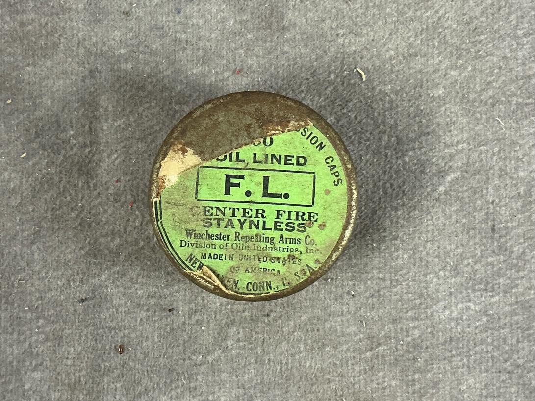 Winchester Percussion Caps: 25 total. Vintage foiled lined caps. Container measures 1.5 inches in diameter X 5/8 inch high.