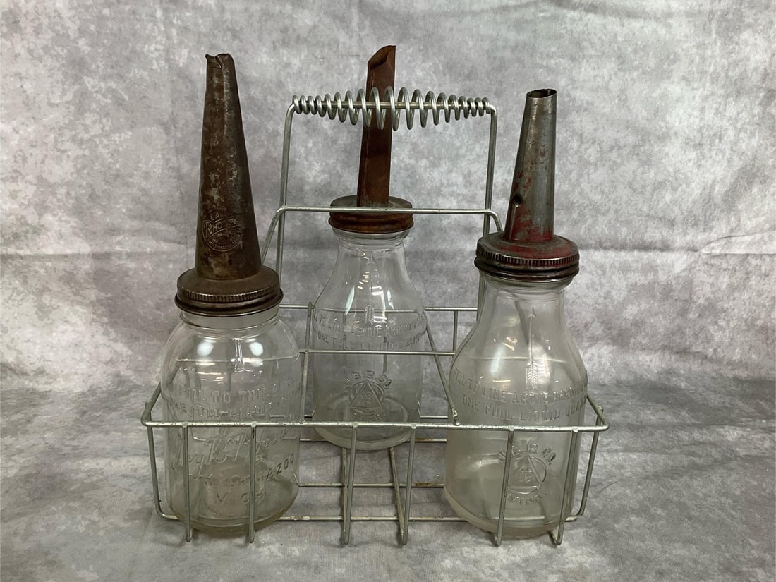 Antique Motor Oil Bottles & Carrier: Mid century bottles. Three J B Rhodes Company glass motor oil bottles with metal spoouts. Includes wire caddy. Rust present on spouts. Otherwise In good condition. Caddy measures 13 inches wide x 9 x