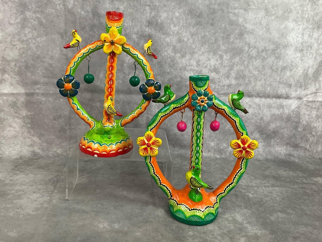 Mexican Tree of Life Candelabras: Pair of mid century candle holders. Mexican colorful folk art Tree of Life candelabras. Hairline crack in top and small chip on candelabra with red and yellow birds. Otherwise in good condition.