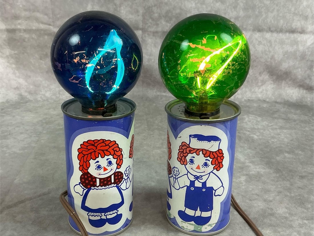 Raggedy Ann & Andy Novelty Lights: Two 1970's lights. Flickering bulbs in metal can featuring Raggedy Ann & Andy. Bulbs have some scratches, otherwise in good condition. Lights work. Each measures 2.25 inches in diameter x 8.25 inches
