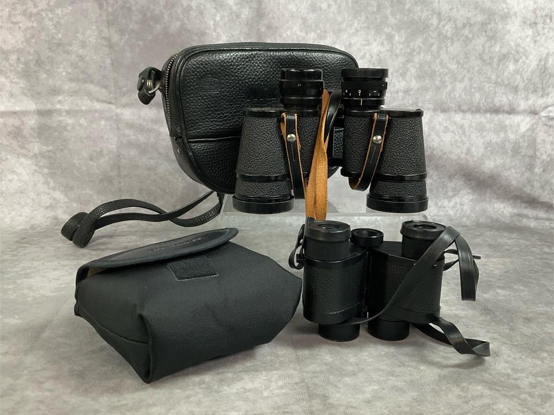 Nikon & Bushnell Binoculars: Two vintage pairs of binoculars. Nikon J-87, 7 x 35, and Field Bushnell Ensign 7 x 25. Both in cases and in good condition. Largest measures 7" across x 2 x 5 inches tall.