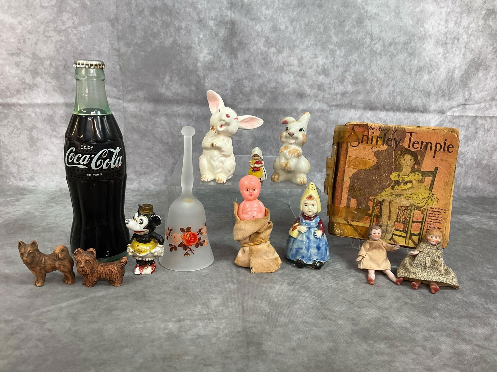 Coke Radio, Bisque Dolls, Bunnies, & more: Thirteen early to mid century items. Includes Coke AM radio (untested), two porcelain bunnies, two bisque miniature dolls, Shirley Temple 1934 book, bisque Minnie Mouse, and more. Items show wear and