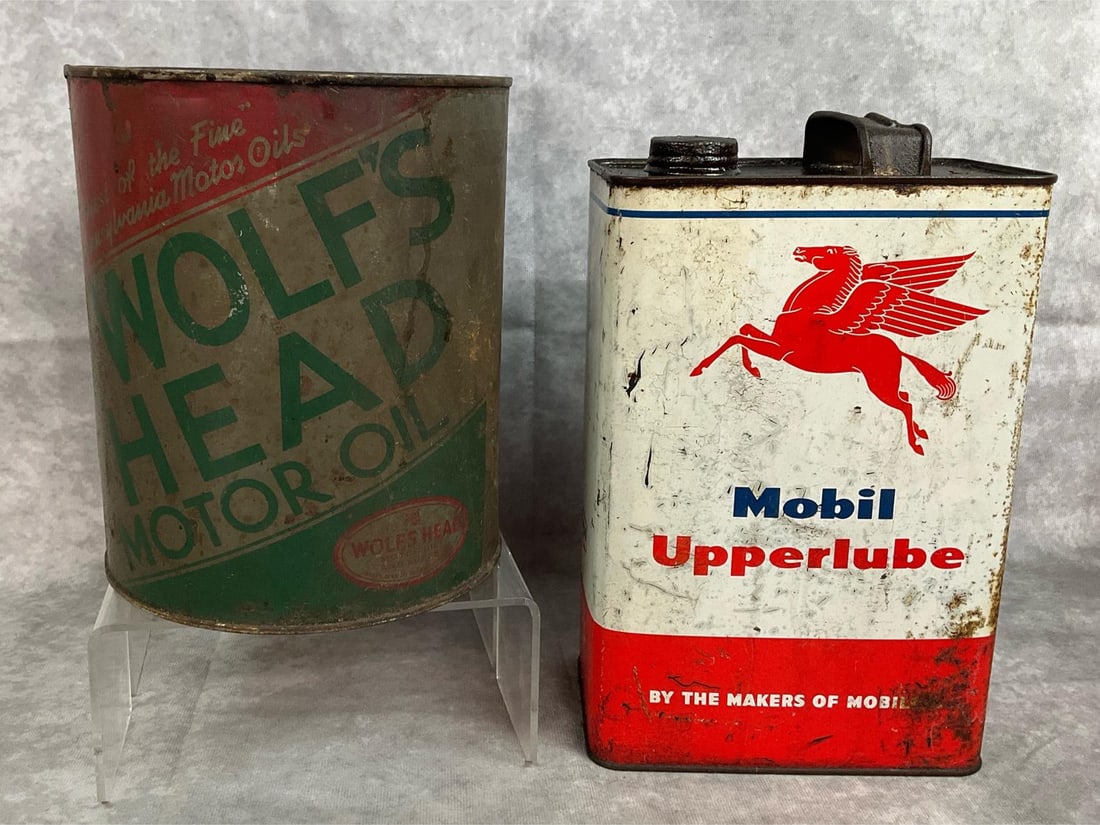 Vintage Oil Cans: Two mid century oil cans. Mobil Upperlube one gallon oil can and Wolf's Head Motor Oil round four quart size can. Both are metal and rusty and worn. In fair condition. Square can measures 6.5 inches