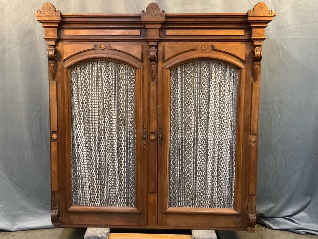 Eastlake Cupboard Top: Circa 1900 Eastlake carved walnut cupboard top (missing bottom half) with iron mesh screen fronts and white lace curtains on interior. One adjustable shelf, three Eastlake style carvings to pediment,