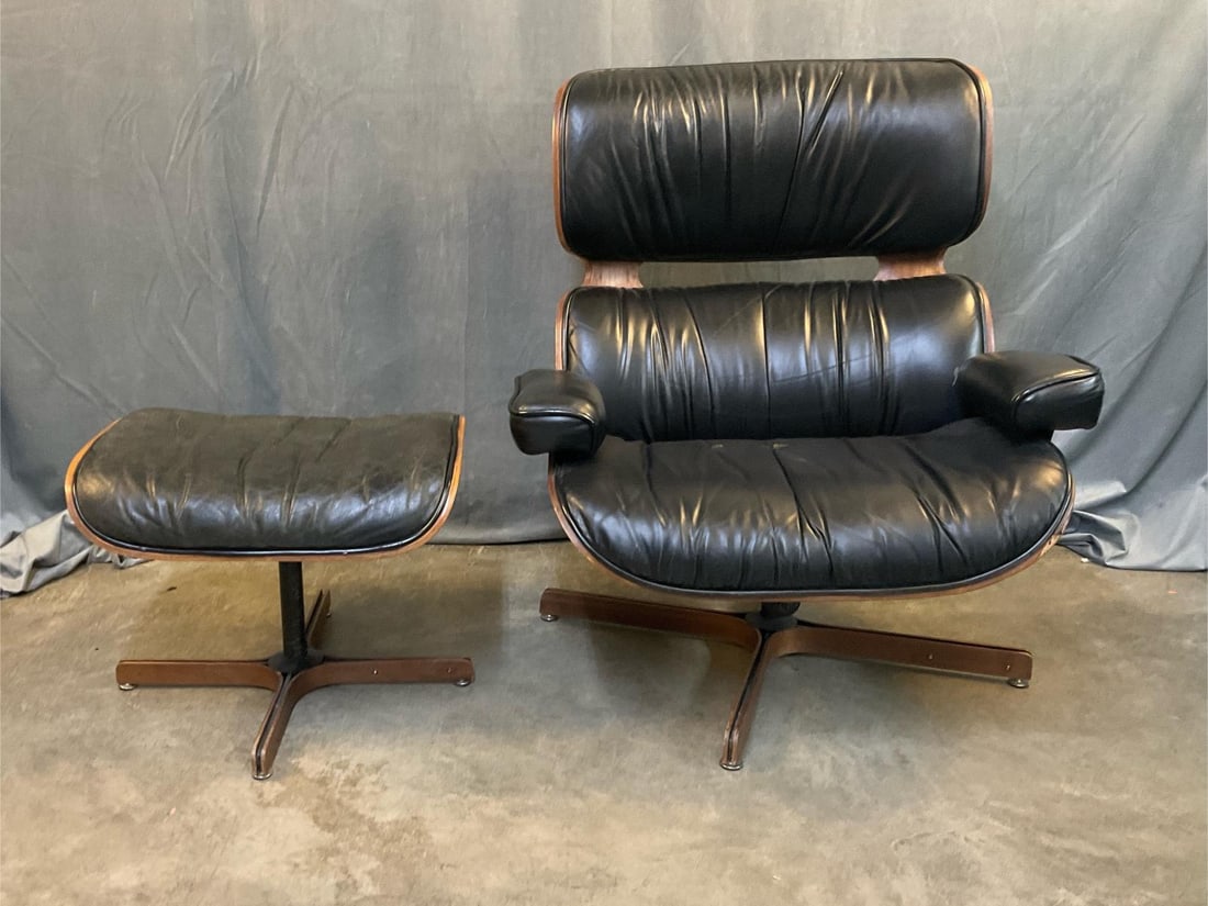 MCM Chair: MCM circa late 1960's Eames style black leather and walnut lounge armchair with matching ottoman/footstool. Walnut veneered plywood, steel and wood base, with pivoting tilt mechanism. Original label m
