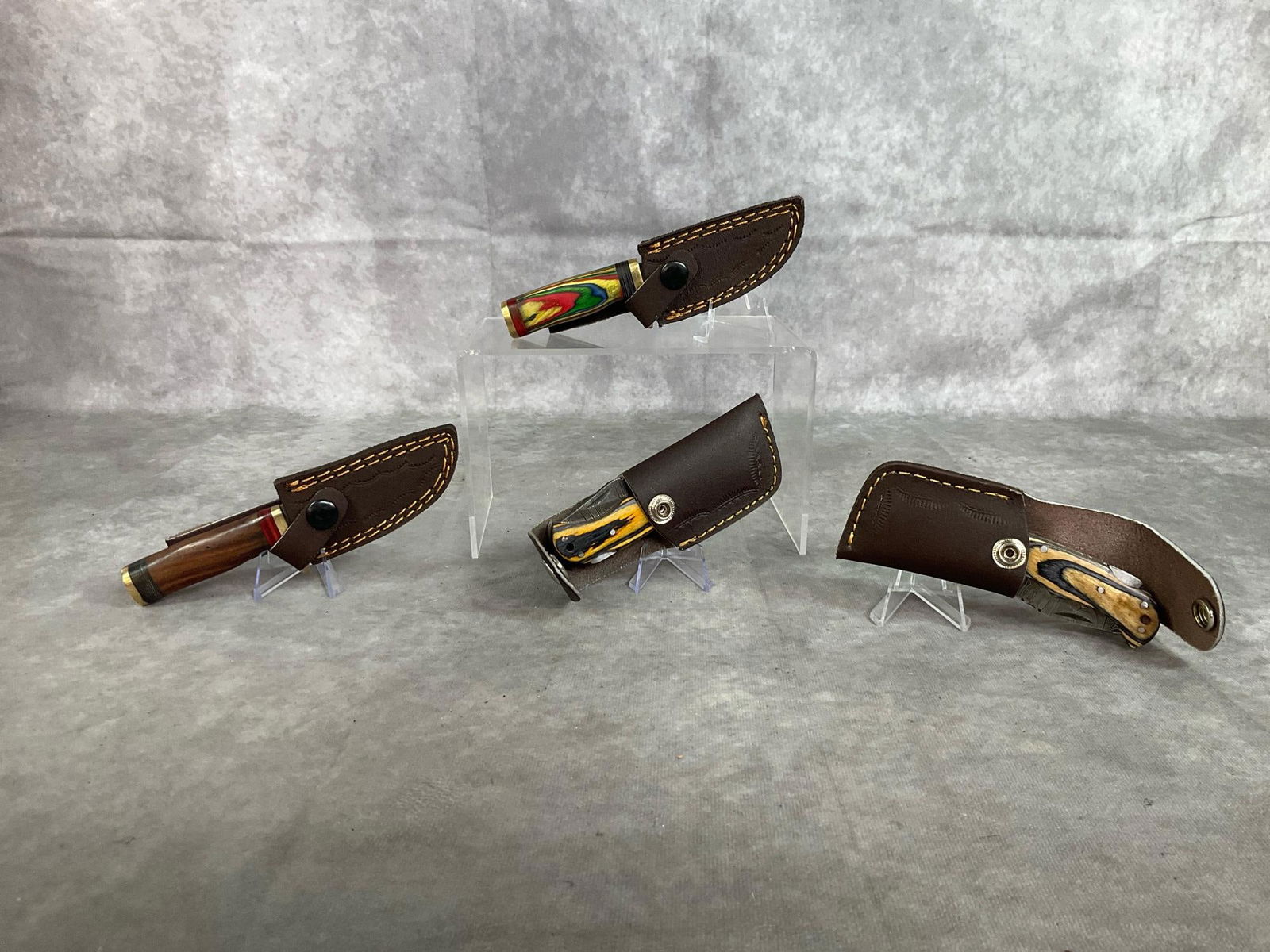 Assorted Knives: Lot of four contemporary 21st century Damascus steel forged hand wrought custom made vintage collectible knives with leather belt sheaths and multi colored pakka wood handles. One 6 inch fixed blade