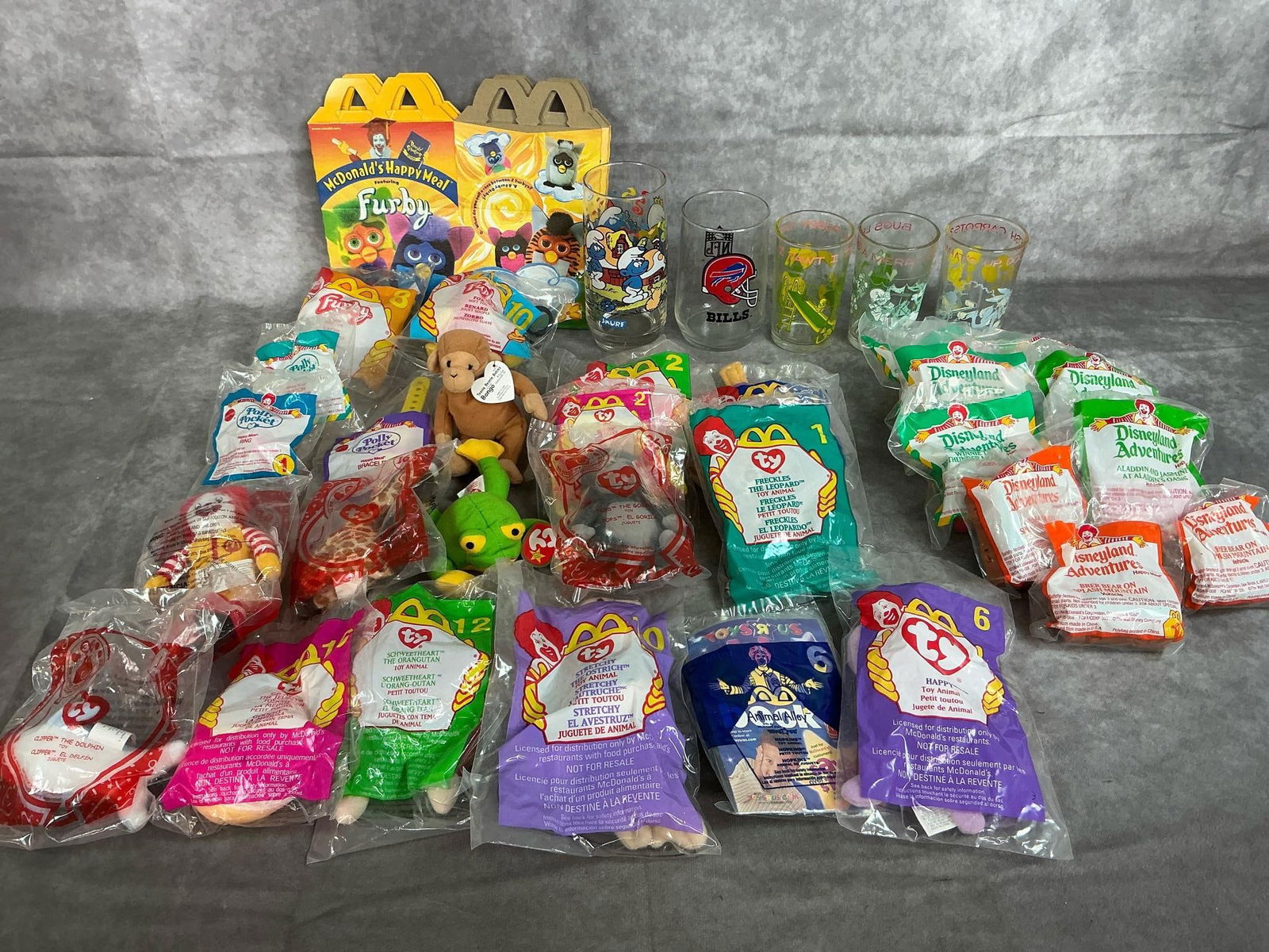 McDonald's Toys & Looney Tune Glasses: Five glasses and twenty-nine toys from 1994 to 2009. McDonald's toys include 15 Ty Animals, 9 Disneyland Adventures toys, 3 Polly Pocket, and 2 Furby toys with boxes. Glasses include a Smurf glass, a