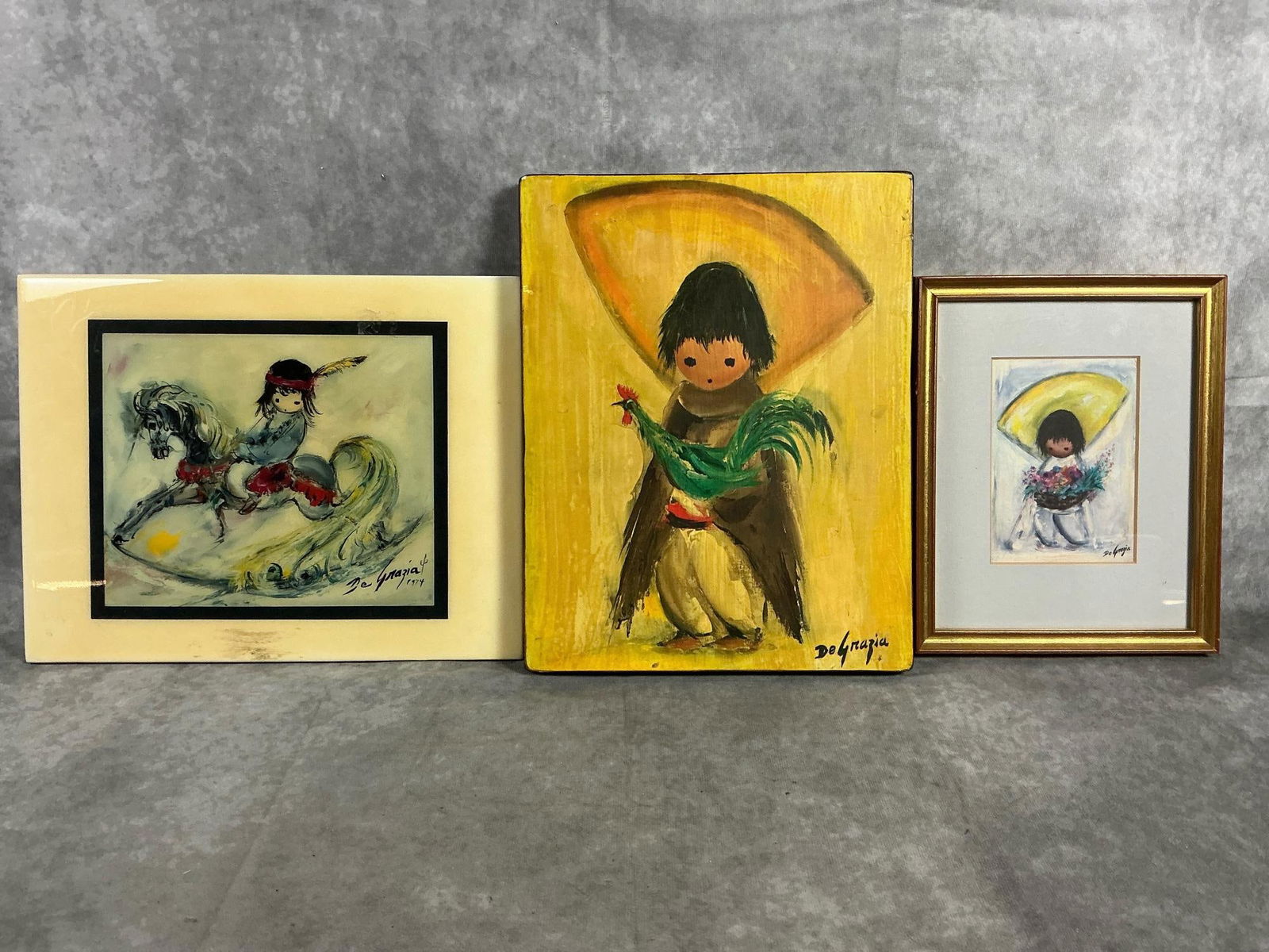 DeGrazia Art: Three late century art pieces. Southwestern art by Ted DeGrazia. Includes tile with painting of Native American child on rocking horse, boy and rooster on wood block, and framed picture of boy with