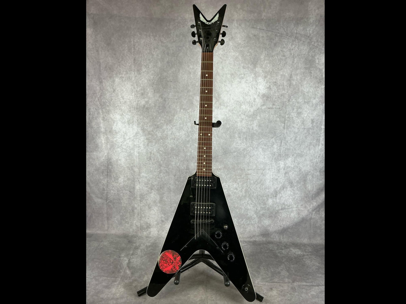Dean VX Flying V Electric Guitar: Dean vx Flying V v shaped body from basswood in black finish with Dean sticker six string electric guitar. Three volume/tone knobs, three way selector switch. Serial number J18040960. Bridge, neck,