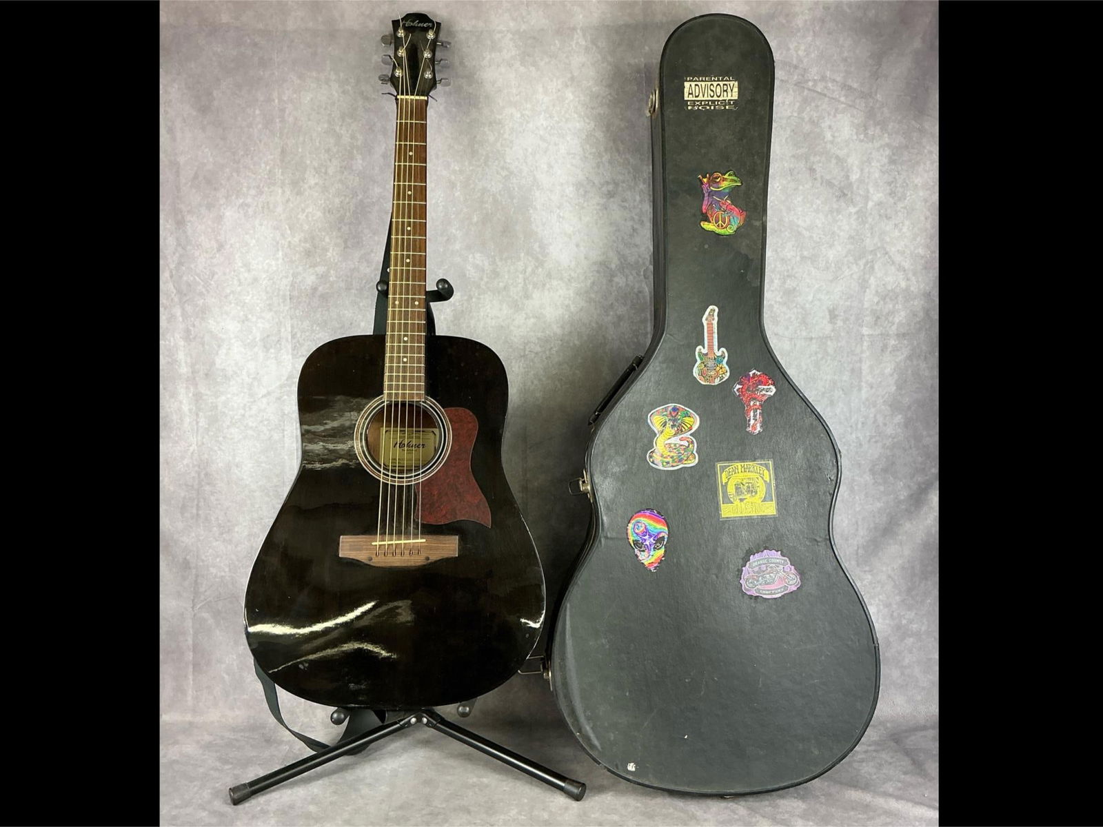 Honer Acoustic Guitar: Model 4105 six string acoustic guitar, model number HW300G-TBK. Black body with marbled red and black pickguard, black leather shoulder strap made by Martin, and a hard shell case included. Guitar is