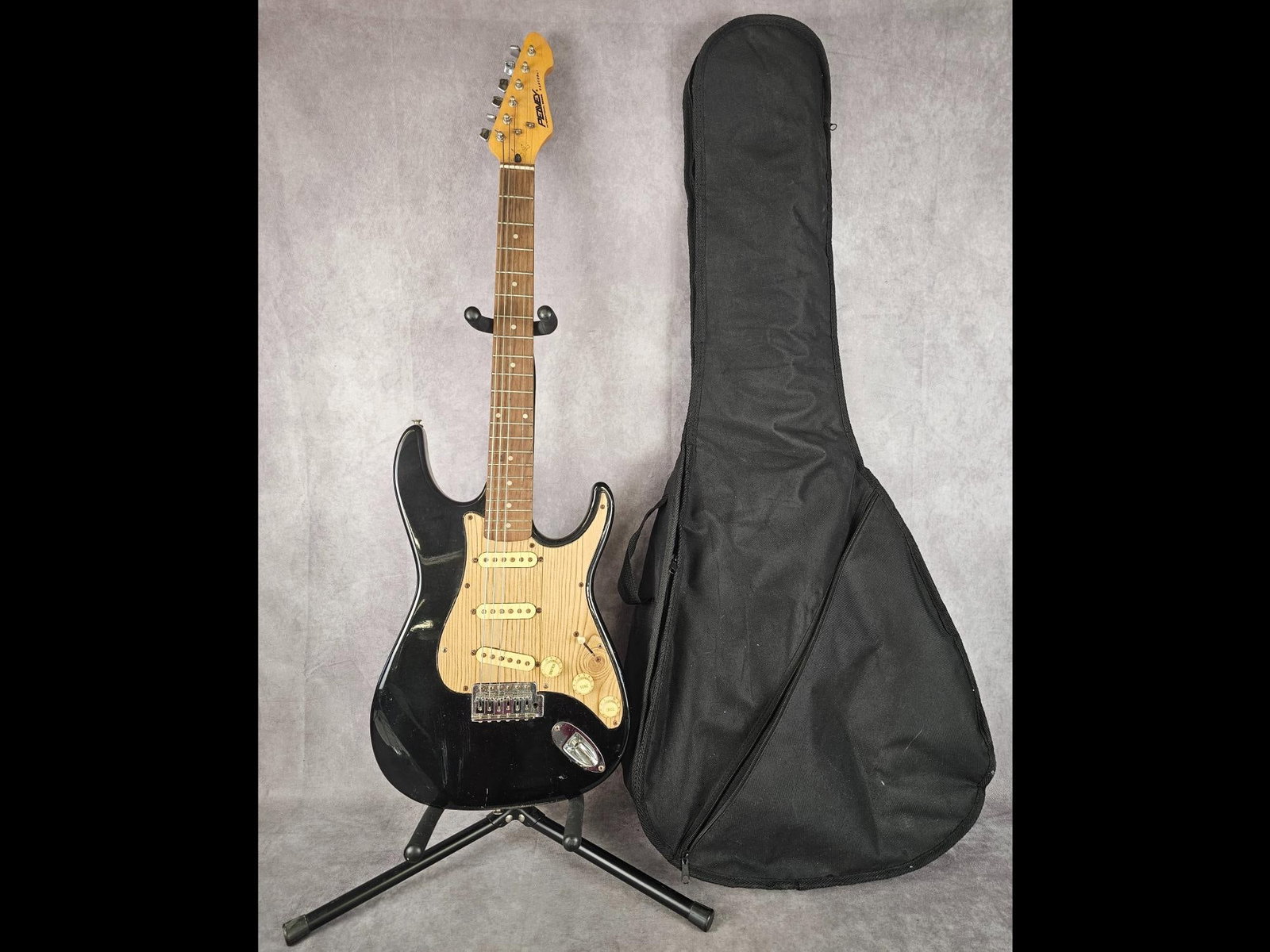Peavy Electric Guitar: Peavy Raptor 1 International series Stratocaster electric guitar with woodgrain pickguard. Four way selector switch, three tuning nobs, and a soft shell case included. Wear to body, scratches to