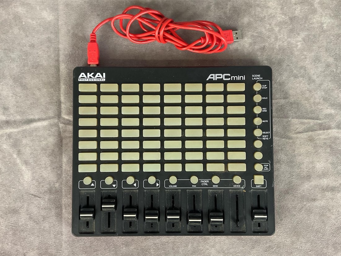 Akai Pro APC Mini: Model APC mini. Serial number (21)BA1405159501735. 8x8 button grid, eight faders, one master fader, usb port. Good used condition, untested. Measures 9.5 inches wide x 8 x 1 inch tall. Comes with usb
