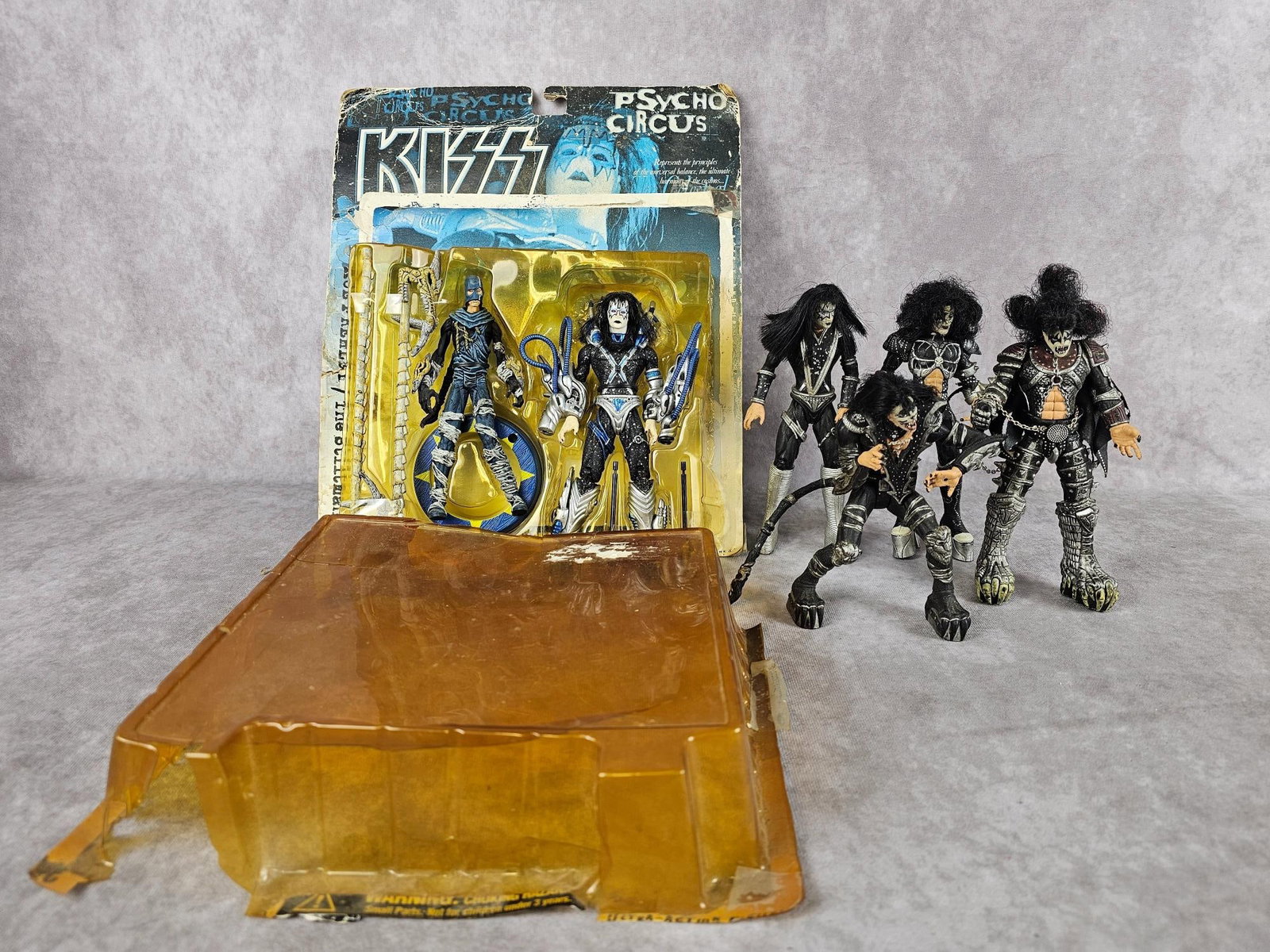 KISS Action Figures: Four 1998 loose action figures and a set of 1998 figures new with packaging. Loose figures show signs of heavy use. New figures are loose from cardboard backing and front plastic has yellowed. Packagi