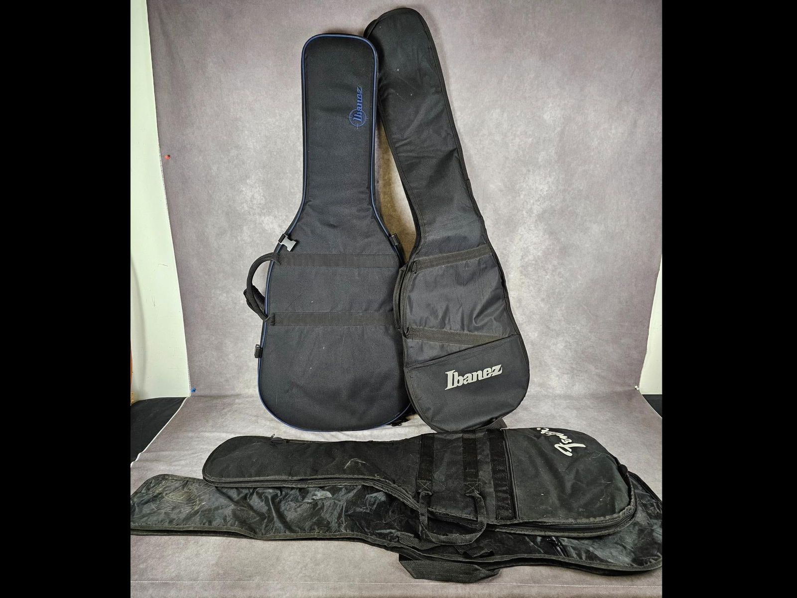 Guitar Cases: Lot of four soft shell guitar cases. One structured soft case made by Ibanez, soft Ibanez case, Fender, and unbranded. Good used condition, Fender case has a broken piece for the shoulder strap. Ibane
